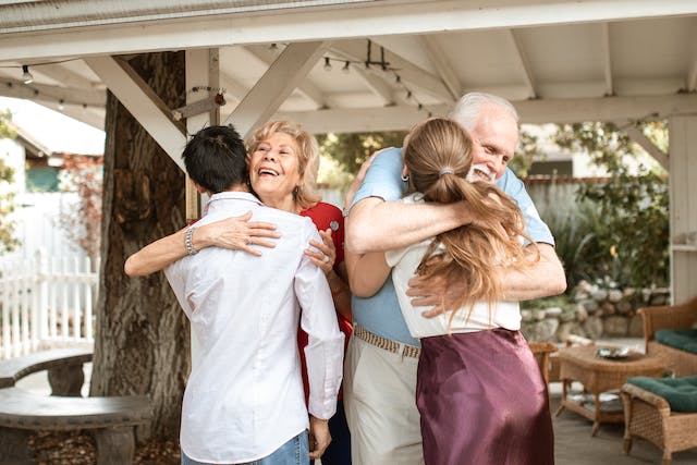 estate planning solutions, image of an older man and woman hugging younger male and female